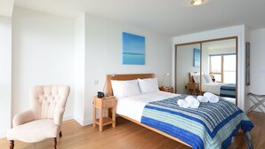 A bedroom with a bed, a chair, a nightstand, and a mirror. - Glas Mor (St Ives)