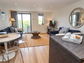 A modern living room with a sofa, a coffee table, a TV, and a dining area. - Bamaluz (St Ives)
