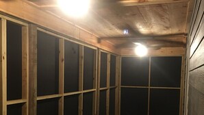 Une pièce en bois à la lumière tamisée, avec un plafond en pente et une seule source de lumière visible.