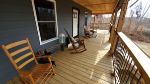 Une terrasse en bois avec une chaise berçante et un banc.