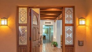 Un passadís amb portes de fusta i panells de vidre que condueix a una habitació amb una creu a la paret.