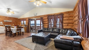 L’intérieur d’une cabane en rondins comprend un coin repas, un canapé en cuir et offre une vue sur l’extérieur.