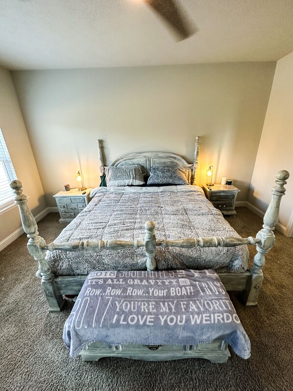 A bedroom with a four-poster bed, two bedside tables, and a ceiling fan.