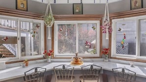 A dining area with a round table and chairs, large windows with decorative elements, and a view of the outside. - Beautiful Victorian in Downtown Cheboygan (Cheboygan)