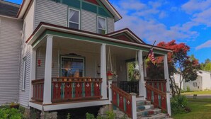 A two-story house with a porch, a front door, and a small front yard. - Beautiful Victorian in Downtown Cheboygan (Cheboygan)