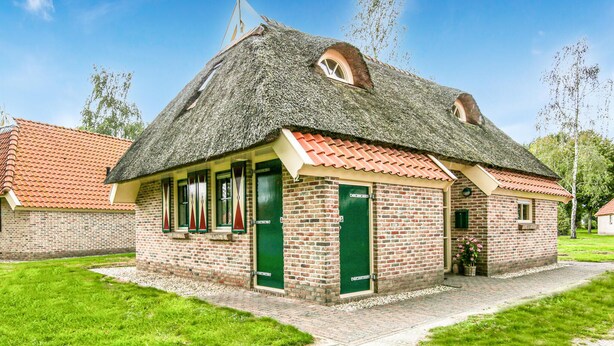 A traditional brick building with a thatched roof, green doors, and a small garden area. - Gorgeous home in IJhorst with WiFi (IJhorst)