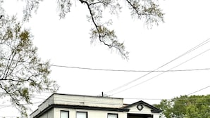 Un edificio blanco de dos pisos con techo negro, un pequeño porche y una bandera estadounidense.