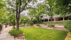A well-maintained garden with a lawn, trees, and a pathway leading to a building. - Modern & Unique Pearl street condo (Boulder)