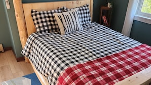 A wooden bed with checkered bedding, a red and white checkered throw blanket, and a blue and white patterned rug. - Riverfront, family fun, amazing rec room, close to Magic & Okemo (Chester)
