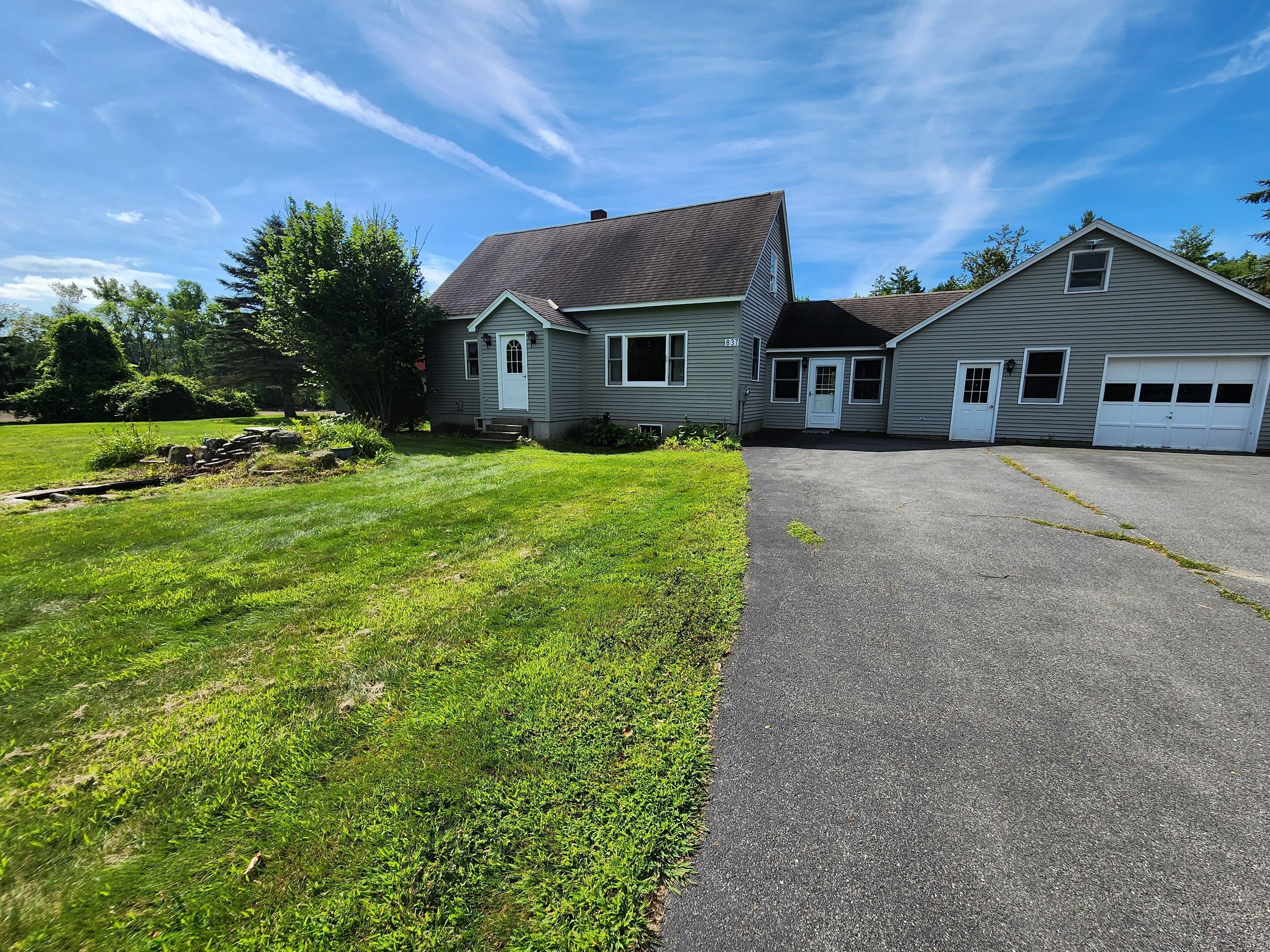 A two-story house with a paved driveway and a well-maintained lawn.