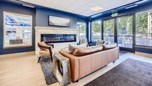 A modern lounge area with a fireplace, comfortable seating, and large windows offering outdoor views. - Ski Slope Steps From Unit, Quick Walk to Main St (Breckenridge)