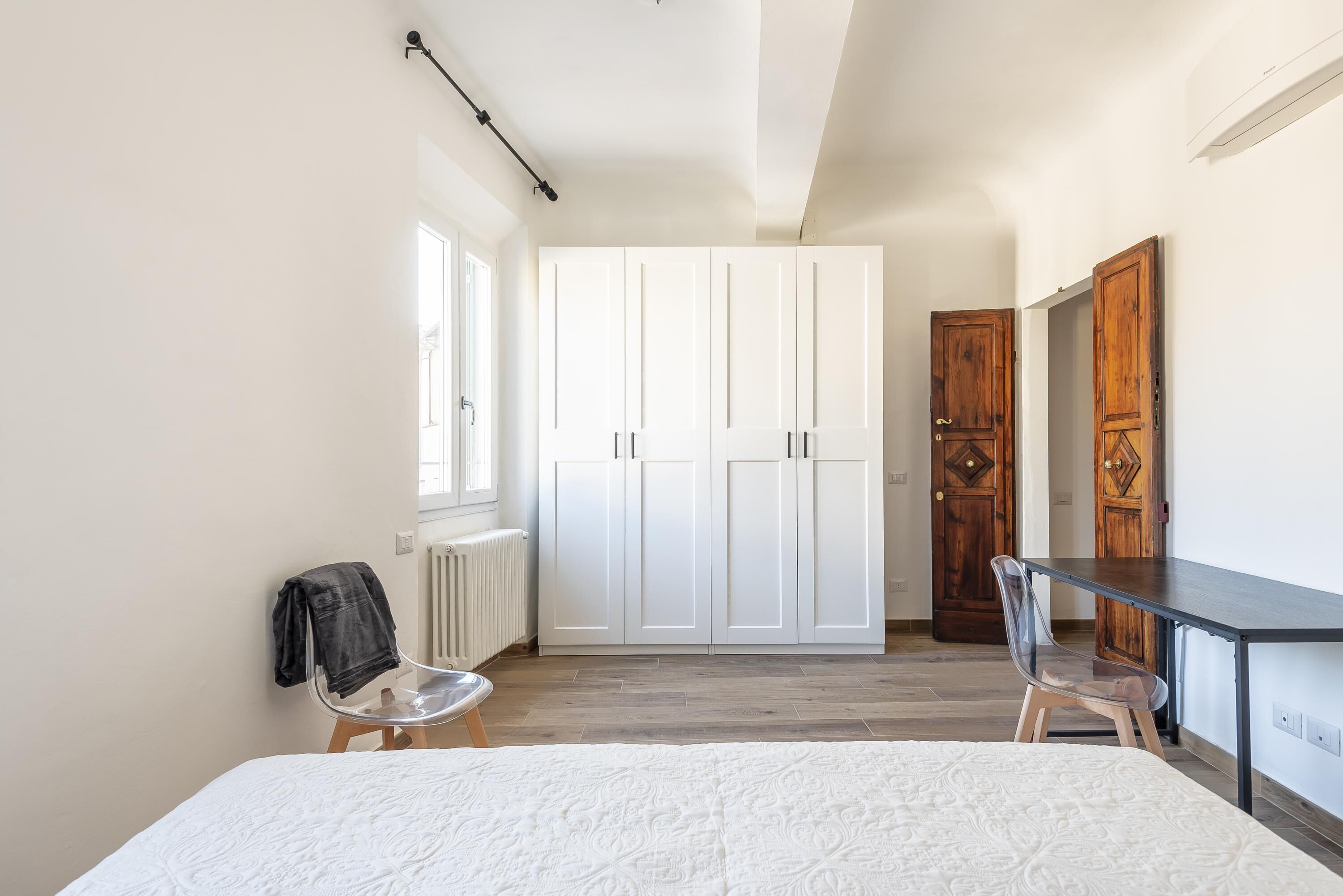 A bedroom with a bed, a desk, and a wardrobe.