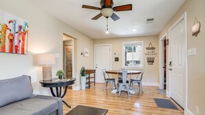 Un salon comprenant un canapé, une table basse, une table à manger avec des chaises, un ventilateur de plafond et un tableau accroché au mur.