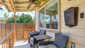 Une terrasse couverte avec un ventilateur de plafond, une clôture en bois et une table avec des chaises.