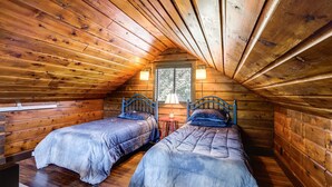 Une cabane avec deux lits en bois, une fenêtre donnant sur un beau paysage et une lampe sur une petite table.