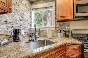 A kitchen with granite countertops, a stainless steel sink, and wooden cabinets.
