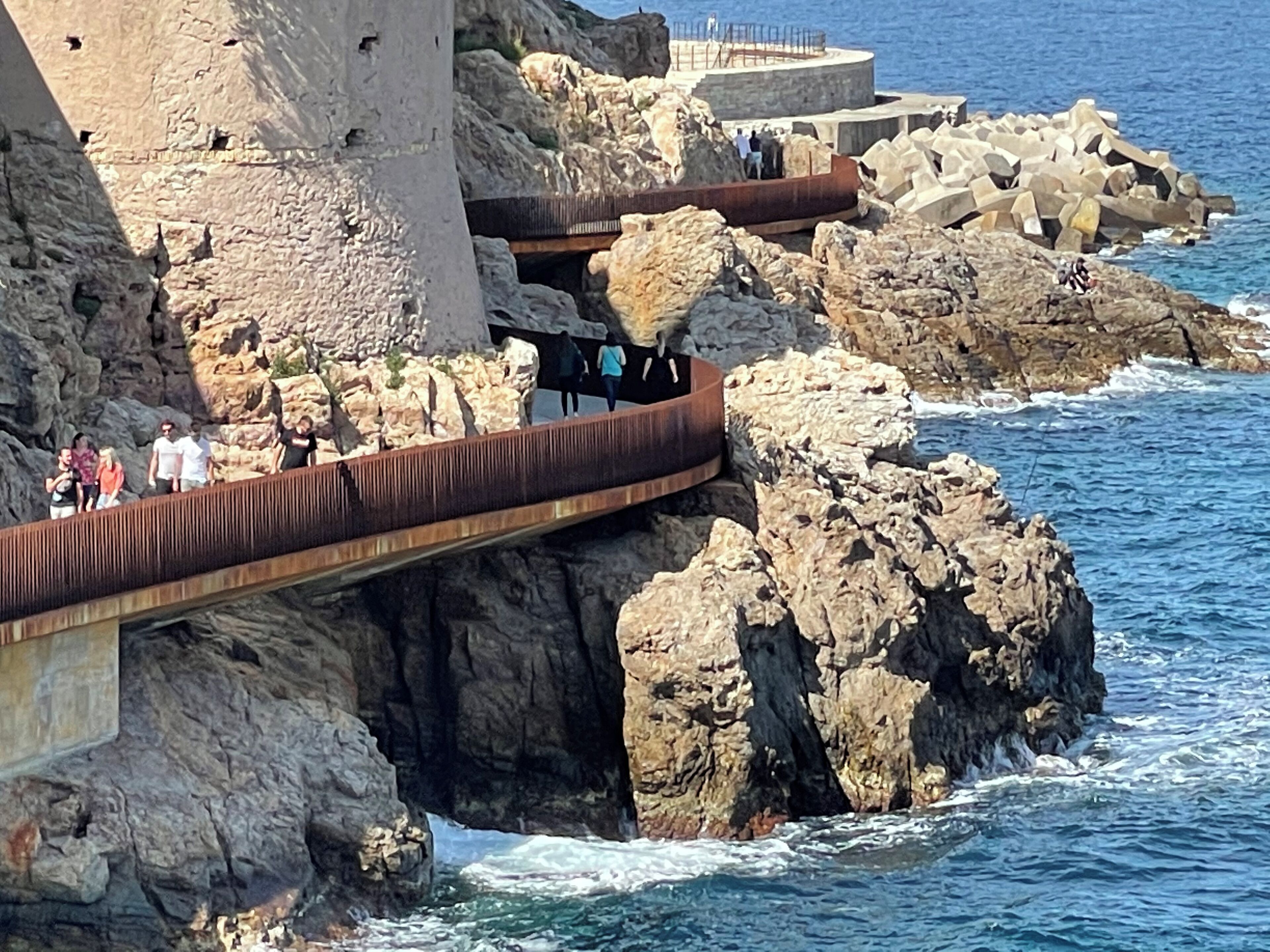 Une promenade en bord de mer, avec des falaises rocheuses et une vue sur l’océan.