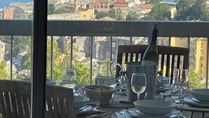 A dining table set with plates, glasses, and cutlery, overlooking a coastal town with historic buildings and a tower. - Extraordinary panoramic  (Bastia)