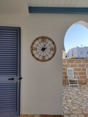 A charming building exterior with a clock, door, and chair.