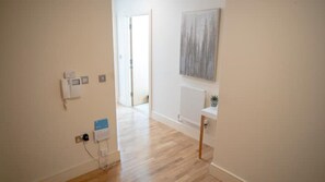 Un couloir doté d’un plancher en bois, d’un radiateur et d’une œuvre d’art accrochée au mur.