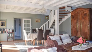 Una sala de estar espaciosa con una escalera, un comedor y una estantería.