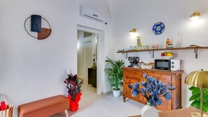 Una cocina moderna con armarios blancos, microondas y un mueble de madera con objetos decorativos.