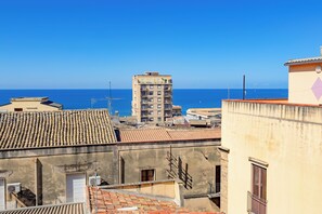 A coastal cityscape with a prominent building featuring multiple balconies and a tiled roof. - L'Antro di Dedalo (Sciacca)