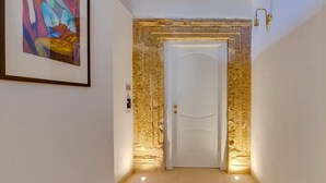 Un pasillo con una puerta blanca, pared de piedra y un cuadro abstracto enmarcado.
