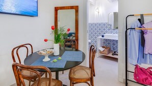 Un comedor con una mesa redonda, cuatro sillas de madera, un jarrón con flores y un espejo grande en la pared.