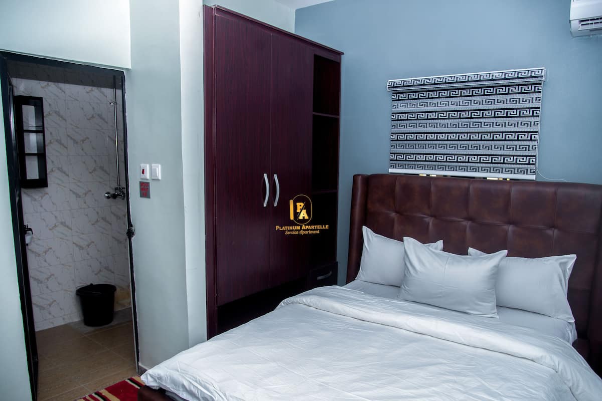 A bedroom with a bed, a wardrobe, and a bathroom visible through an open door.