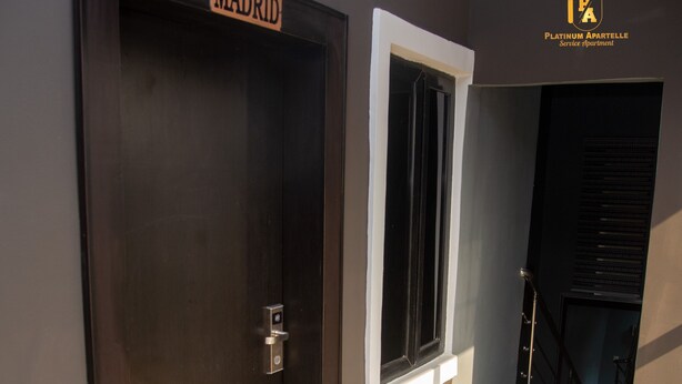 A dark wooden door with a sign that reads "MADRID" and a window with a white frame. - Platinum Apartelle  (Benin City)