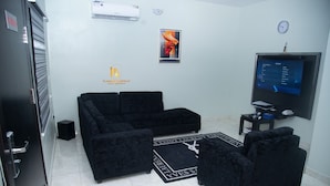 A living room with black sofas, a flat-screen TV, and a small table. - Platinum Apartelle  (Benin City)