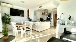 Une cuisine moderne dotée d’un îlot central, un coin repas avec une table et des chaises, et un espace de vie avec un canapé et une table basse.