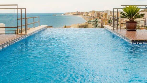 Une piscine offrant une vue sur l’océan et le paysage urbain.