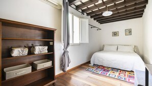 A bedroom with a bed, a wooden shelf with storage boxes, a colorful rug, and a ceiling fan. - Ginori C in Firenze With 3 Bedrooms and 2 Bathrooms (Florence)
