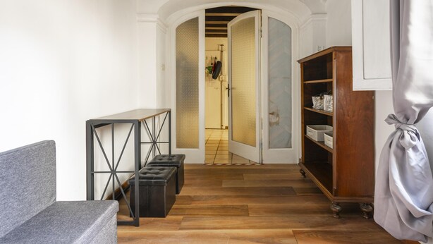 A hallway with a grey sofa, a black metal table, a wooden cabinet, and a door leading to another room. - Ginori C in Firenze With 3 Bedrooms and 2 Bathrooms (Florence)