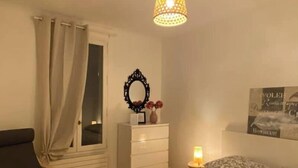 Ein Schlafzimmer mit Bett, Stuhl, Schminktisch, Spiegel und einer Hängelampe.
