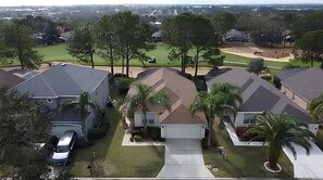 Houses with gabled roofs line a quiet neighborhood surrounded by trees and a golf course.