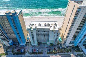 Un hotel de gran altura con estacionamiento, vista a la playa y varios pisos.