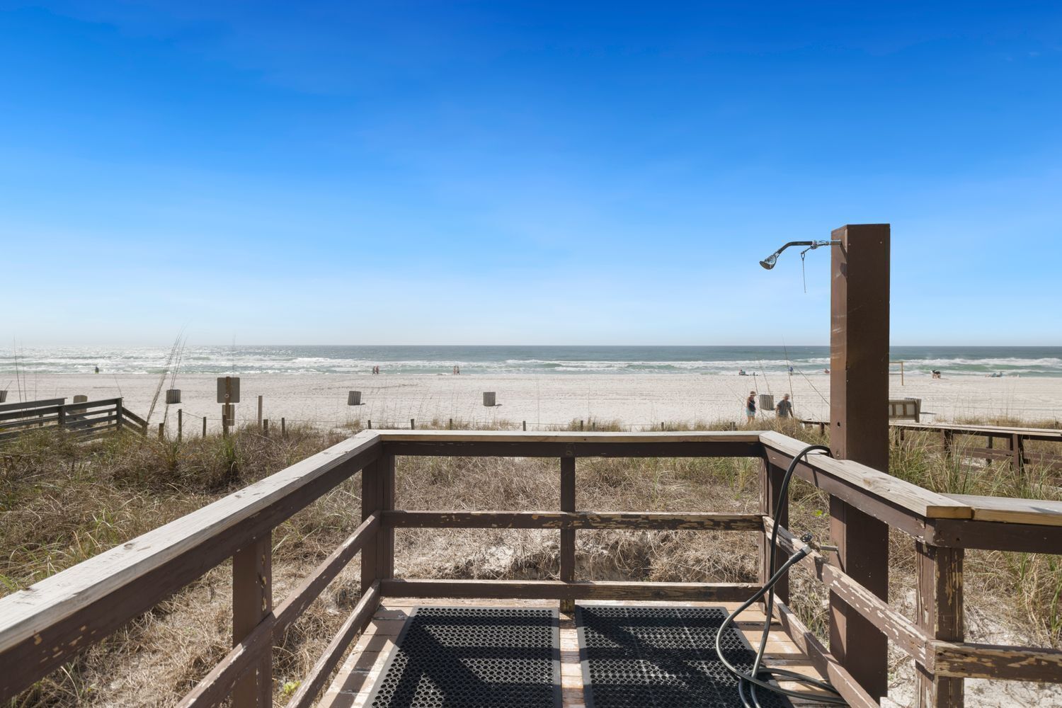 A wooden viewing platform with a metal railing overlooking a beach.