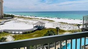 A beach view from a balcony with a pool, sandy beach, and a pier. - Pelican Beach 0614 2 Bedroom Condo by Pelican Beach Management (Destin)