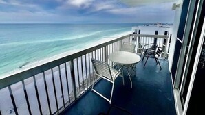 Un balcon avec vue sur l’océan, une table et deux chaises.