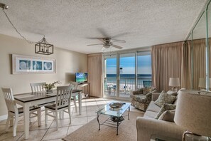 Enjoy a beach view from the large window in this stylish living room, featuring a dining area, comfortable sofa, and TV.
