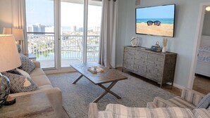 Un soggiorno con divano, tavolino, televisore a parete, mobiletto in legno e balcone con vista sulla città.