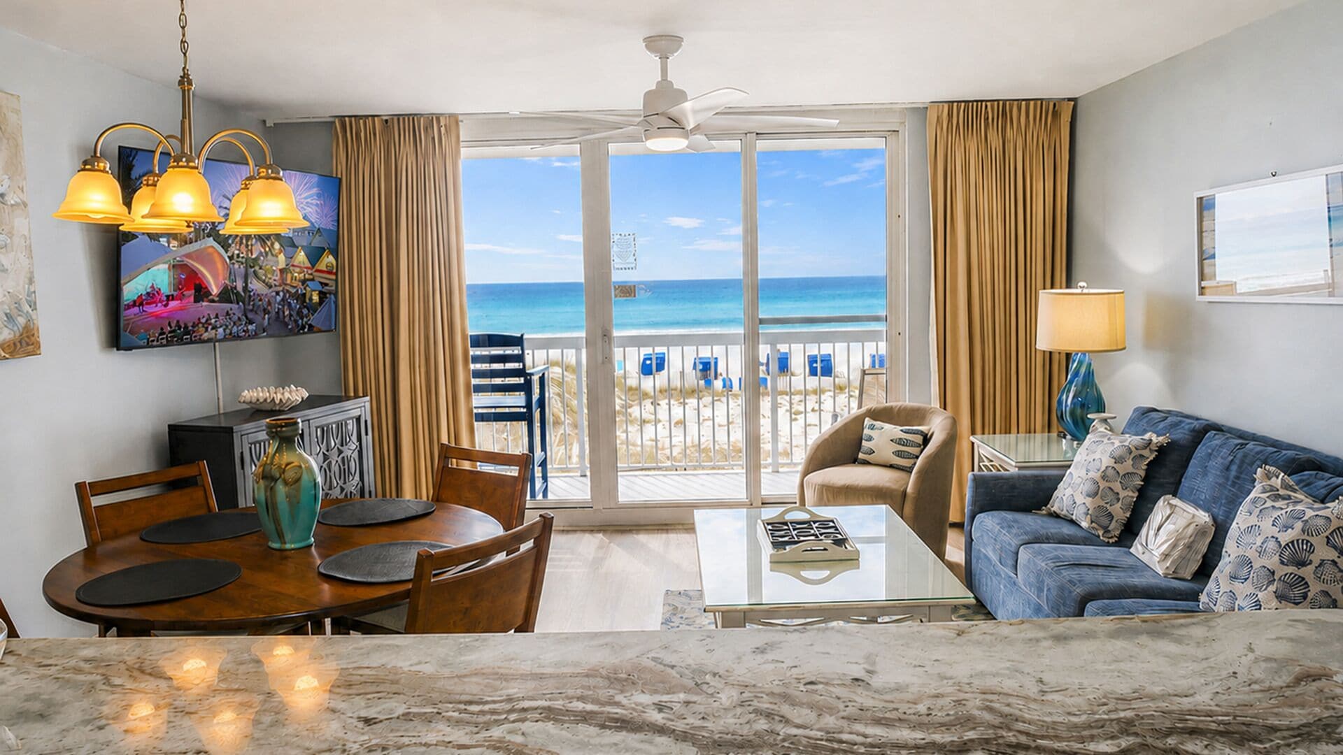 A hotel room with a dining area, a sofa, a coffee table, and a view of the beach.