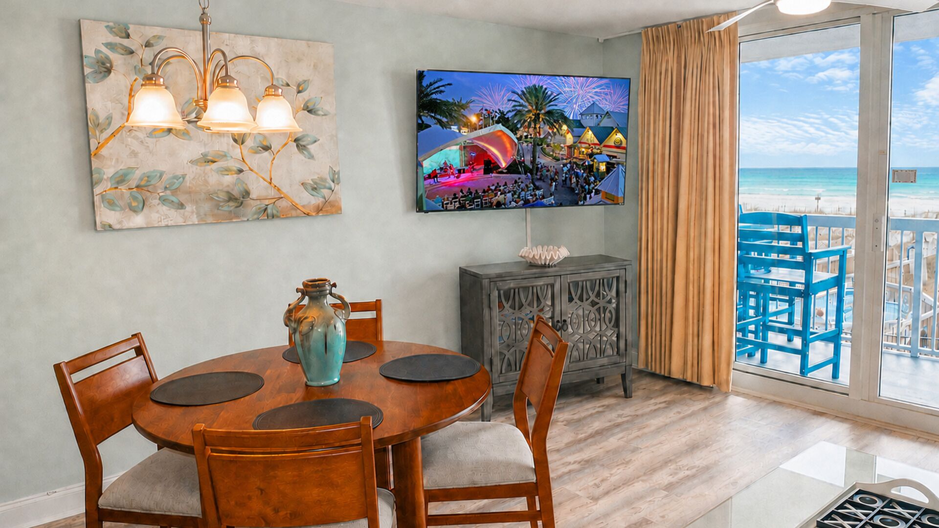 A dining area with a round table, chairs, a vase, and a television displaying a fireworks display.