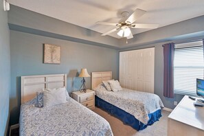 A bedroom with two beds, a ceiling fan, a desk with a computer, and a window with blinds. - Terrace at Pelican Beach 1205 2 Bedroom Condo by Pelican Beach Management (Destin)