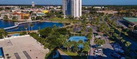 A high-rise hotel with a pool, parking area, and surrounding greenery.