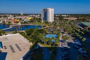 A high-rise hotel with a pool, parking area, and surrounding greenery. - Terrace at Pelican Beach 1205 2 Bedroom Condo by Pelican Beach Management (Destin)