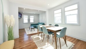 Un comedor moderno con una mesa y sillas de madera, un sofá y un televisor montado en la pared.